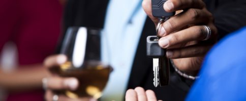 Homem com drink em mãos entregando chaves do carro para outra pessoa