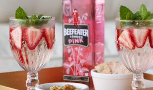 garrafa de beefeater pink entre copos com a bebida, morangos e hortelã