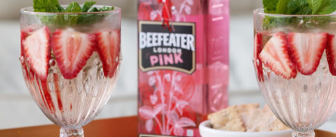 garrafa de beefeater pink entre copos com a bebida, morangos e hortelã