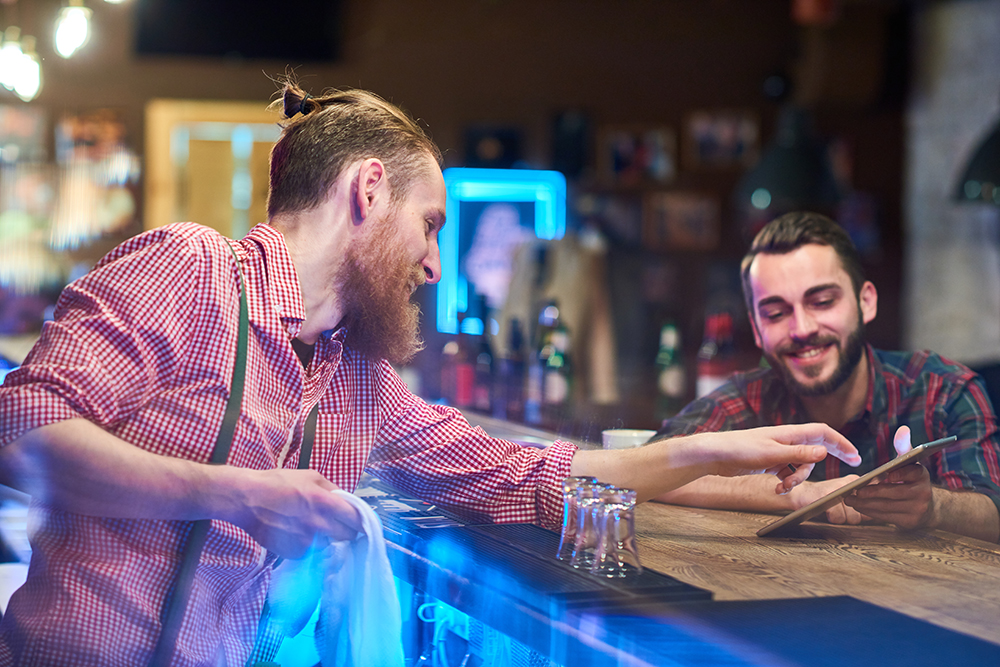 bartender tirando dúvida de cliente no balcão