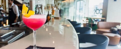 cocktail rosa sobre o balcão de um bar
